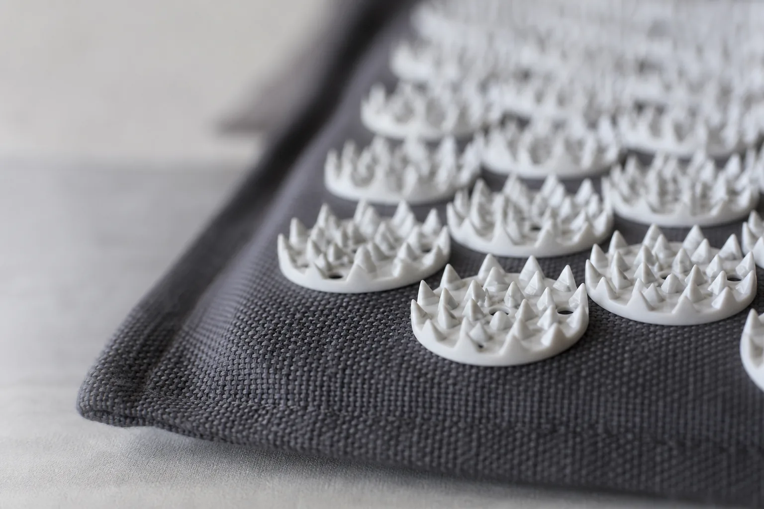 Närbild på en spikmattas piggplattor i textil och plast